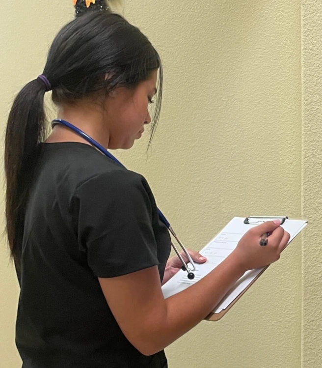 {{ school.name }} student reviewing patient paperwork