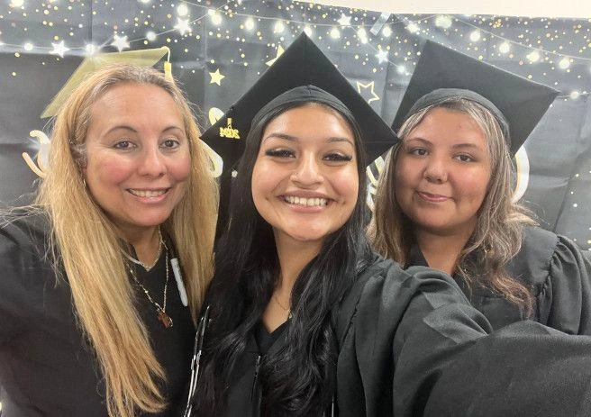 {{ school.name }} graduates posing with congratulatory sign