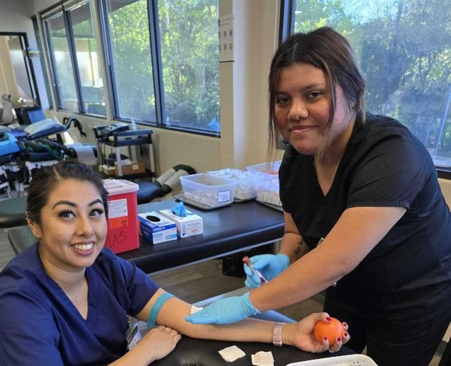 {{ school.name }} students in lab practicing blood draws