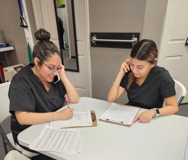 {{ school.name }} students filling out documents for patients