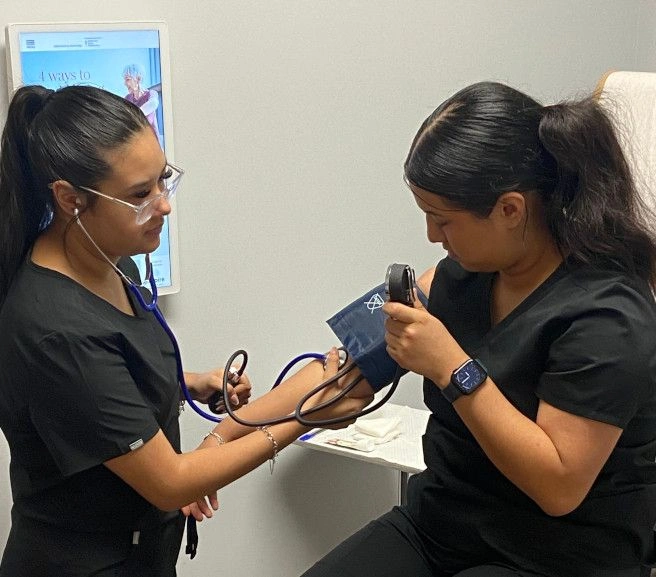 {{ school.name }} students practicing taking blood pressure measurements