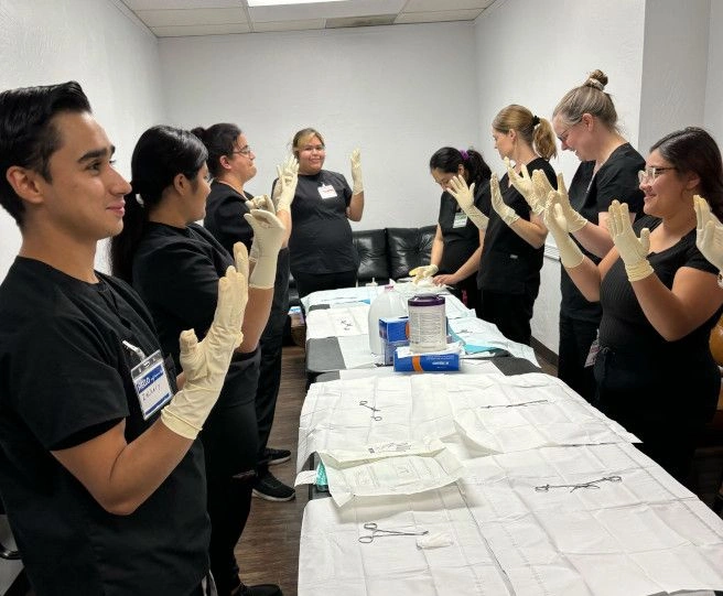 {{ school.name }} students taking a group photo with hands raised with gloves on