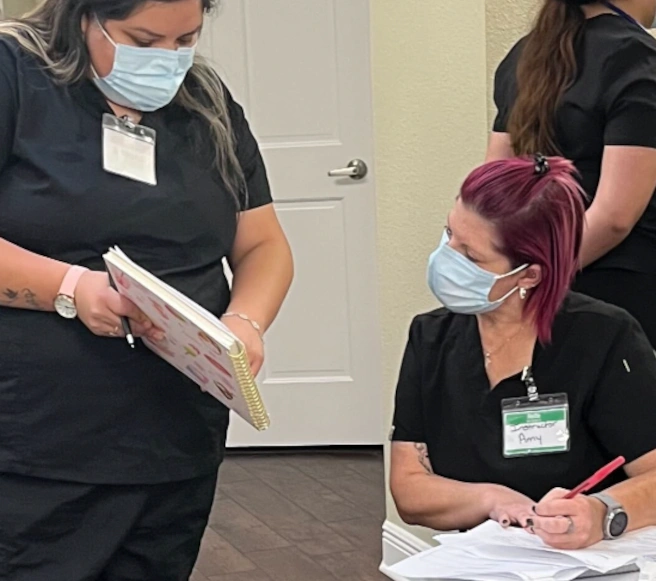 {{ school.name }} instructor reviewing a diagram with a medical assistant student