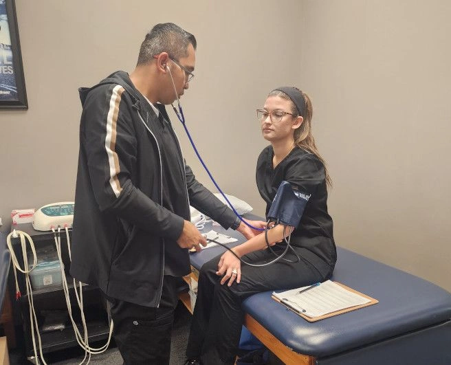 {{ school.name }} student taking another student's blood pressure