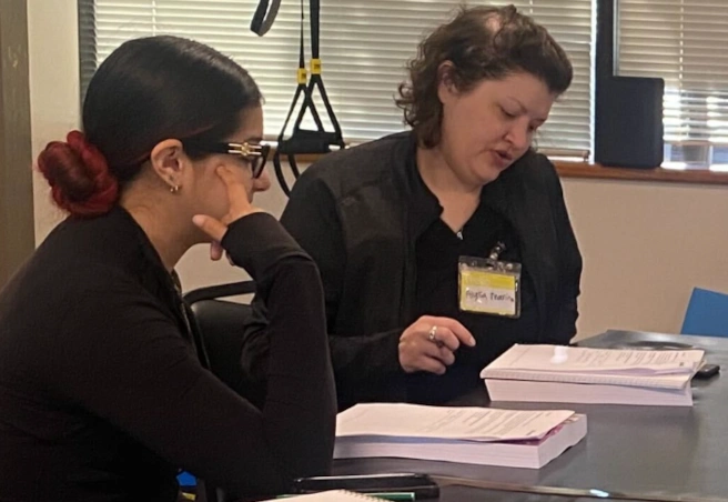 {{ school.name }} instructor reviewing written material with a student