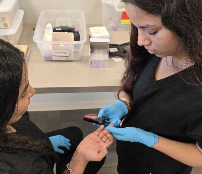 {{ school.name }} student training to take blood from a finger prick